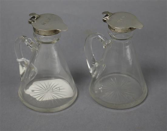 A pair of Edwardian silver mounted glass whisky tot jugs, Hukin & Heath, Birmingham, 1908, 10.5cm.